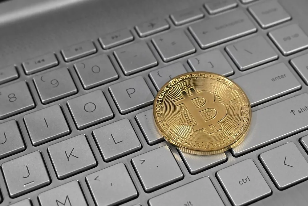 A physical Bitcoin token resting on a laptop keyboard.