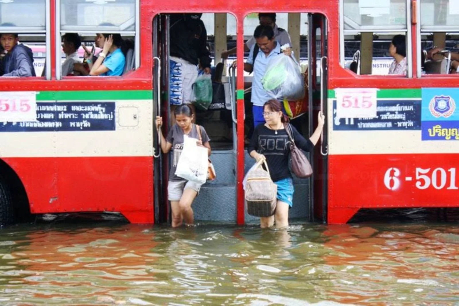 Commuters leave a bus into floodwater in Bangkok